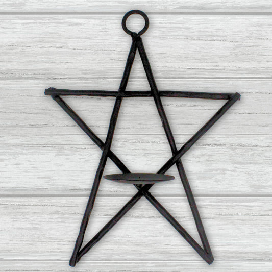 Black star-shaped candle holder on a light wooden background