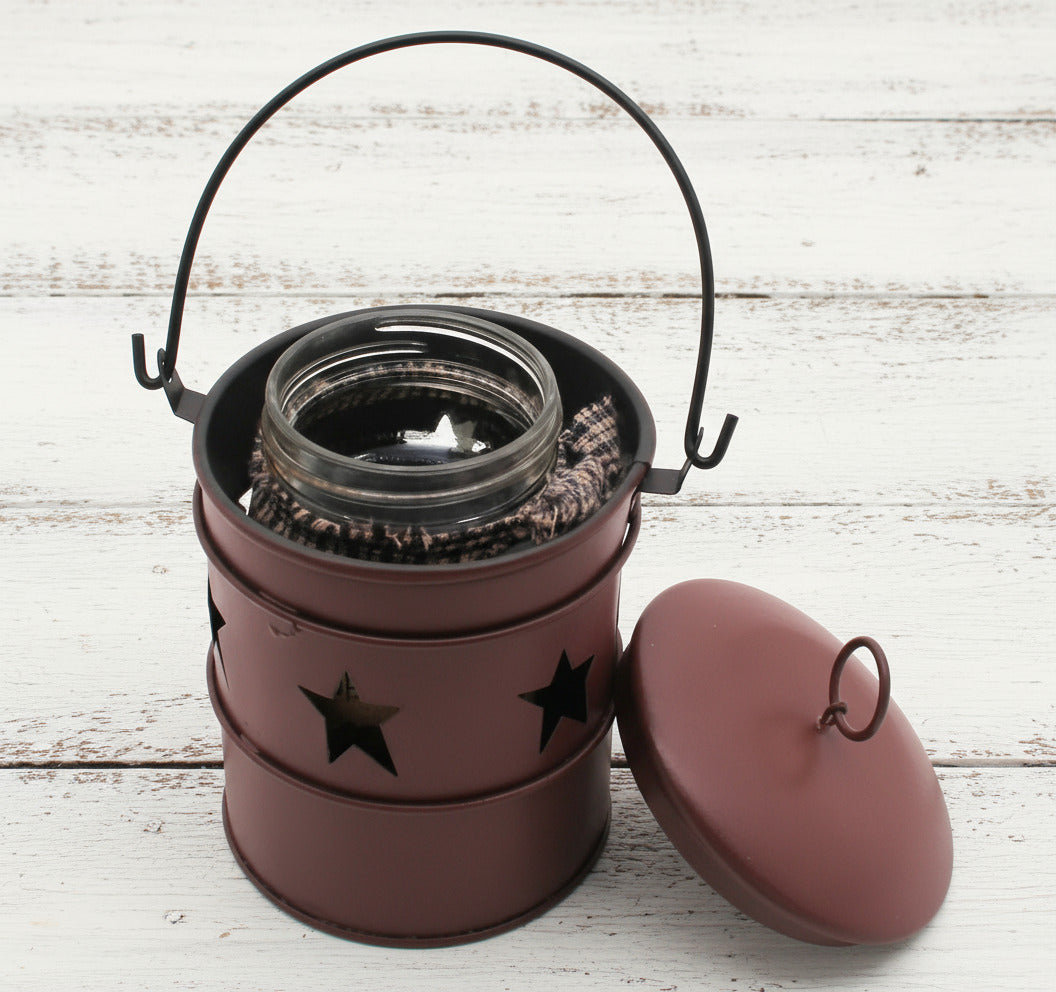 Burgundy metal bucket candle holder with star designs on a white background