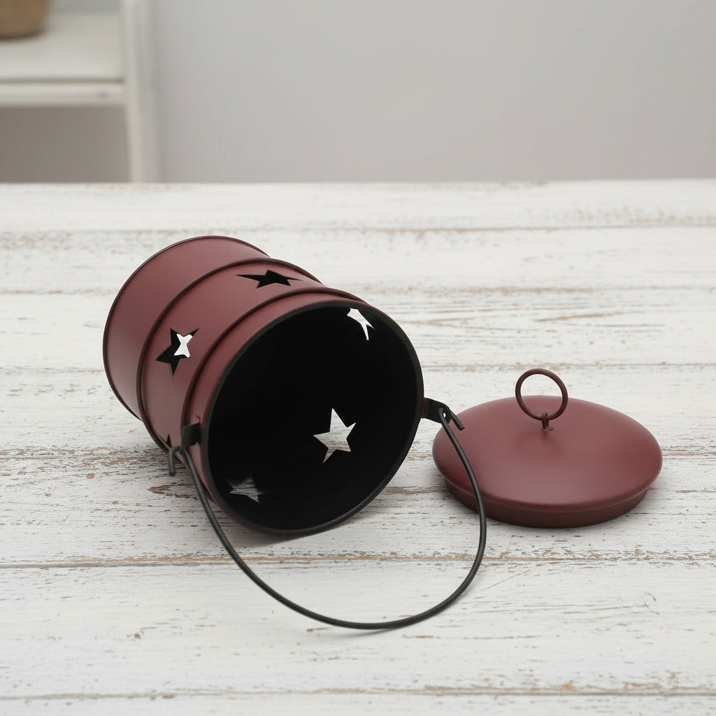 Decorative metal bucket candle holder with star designs on a white background