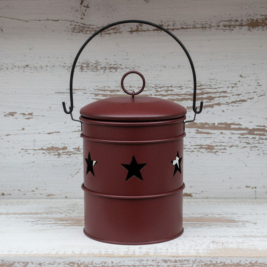 Red metal bucket candle holder with black star designs and a handle on a white background