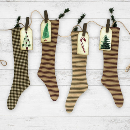 Four striped Christmas stockings with decorative tags on a white wooden background