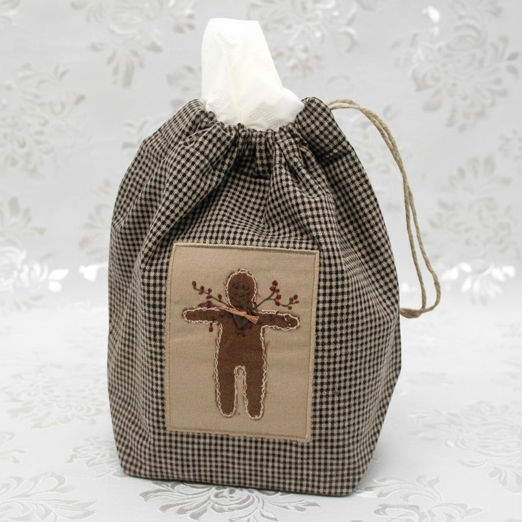 Checkered drawstring bag cube tissue box cover with embroidered gingerbread design on a white background