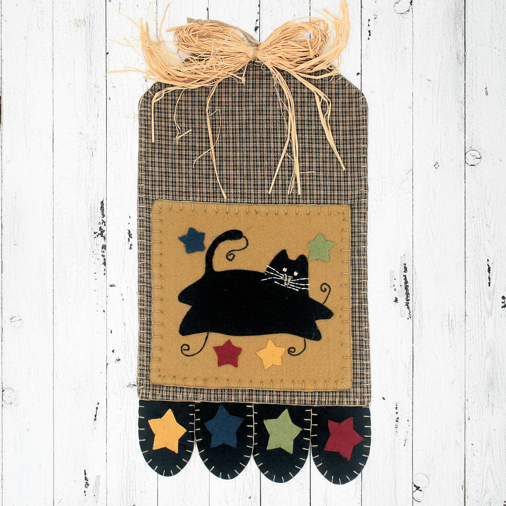 Decorative wall hanging with a black cat design on a wooden background