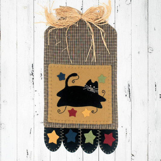 Decorative wall hanging with a black cat design on a wooden background