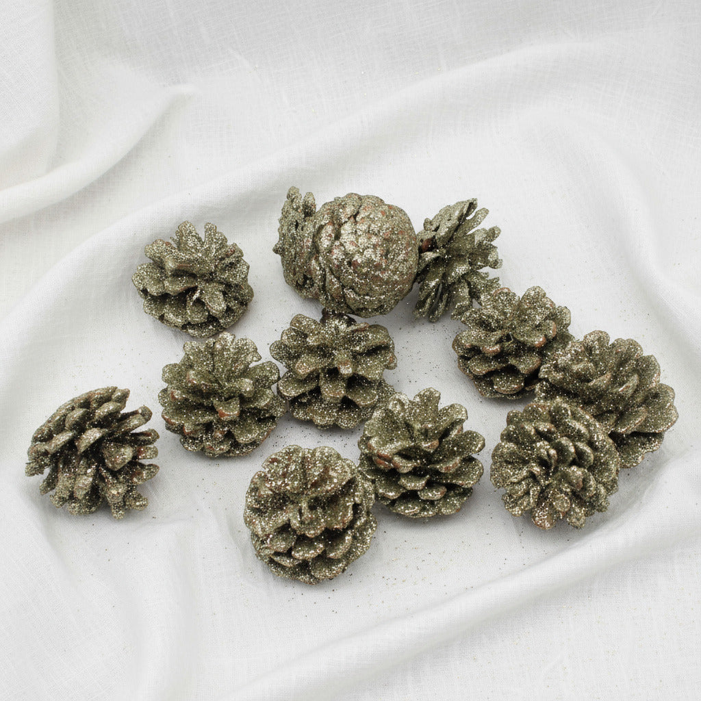 Decorative pinecones with a glittery metallic finish on a white background
