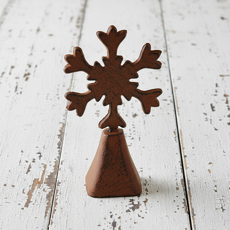 Rust-colored metal cowbell with snowflake-shaped top on a white background