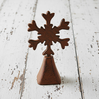 Rust-colored metal cowbell with snowflake-shaped top on a white background