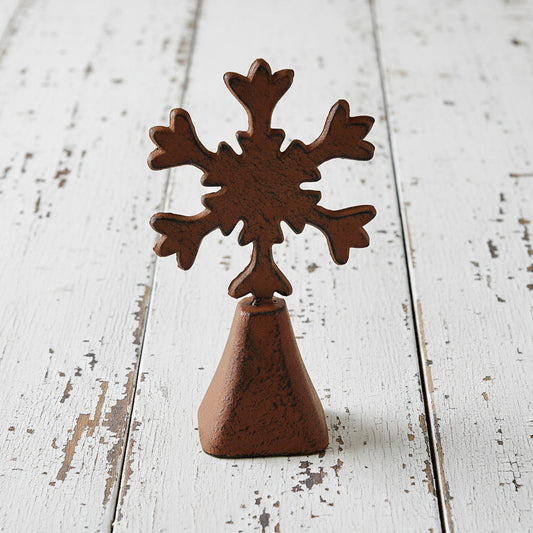 Rust-colored metal cowbell with snowflake-shaped top on a white background