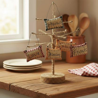 Decorative tree with hanging fabric signs on a wooden surface