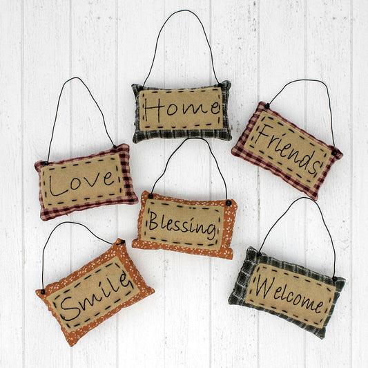 Set of hanging fabric signs with motivational phrases on a white wooden background