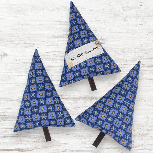Three blue patterned Christmas trees on a wooden surface with 'tis the season!' tag.