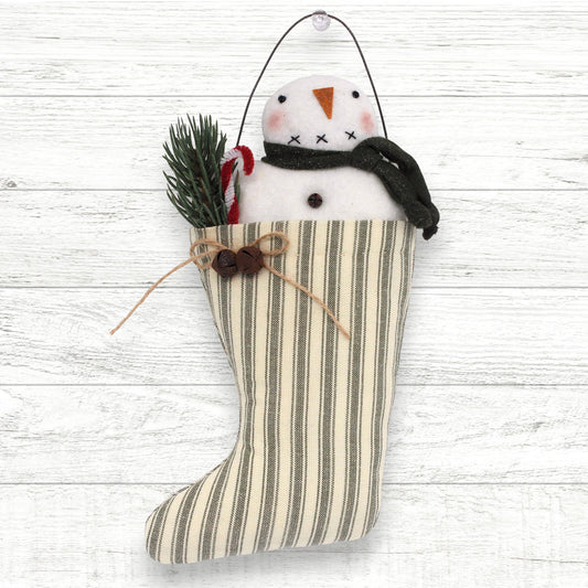 Striped Christmas stocking with a snowman decoration on a white wooden background