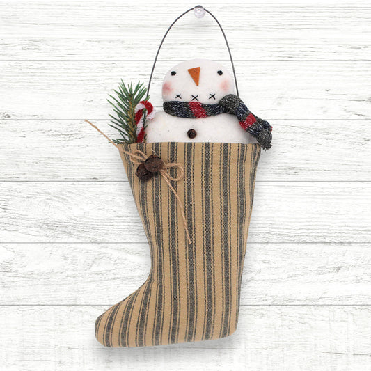 Striped Christmas stocking with a snowman decoration on a white wooden background