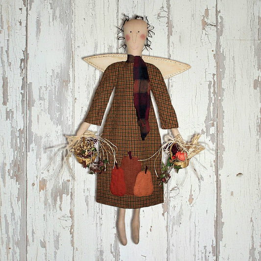 Textile angel doll with plaid dress and autumn-themed accessories on a wooden background