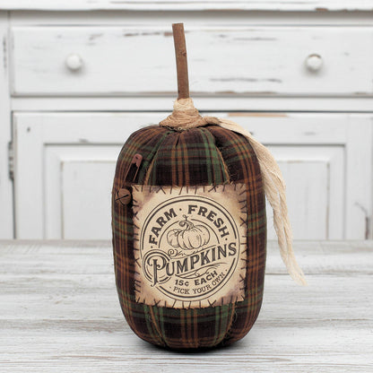 Decorative pumpkin with plaid pattern and 'Farm Fresh Pumpkins' label on a wooden surface.