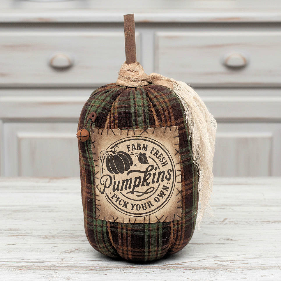 Decorative pumpkin with plaid pattern and 'Farm Fresh Pumpkins' label on a wooden surface.