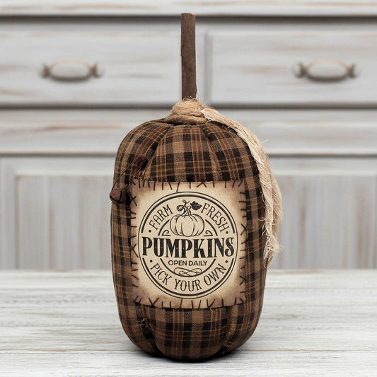 Decorative grungy homespun handcrafted pumpkin with plaid pattern and 'Farm Fresh Pumpkins' text on a wooden surface.