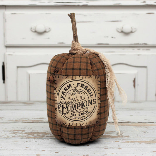 Fabric pumpkin with 'Farm Fresh Pumpkins' label on a wooden surface