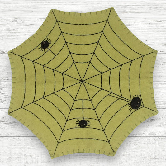 Hexagonal green fabric with spider web design on a white wooden surface