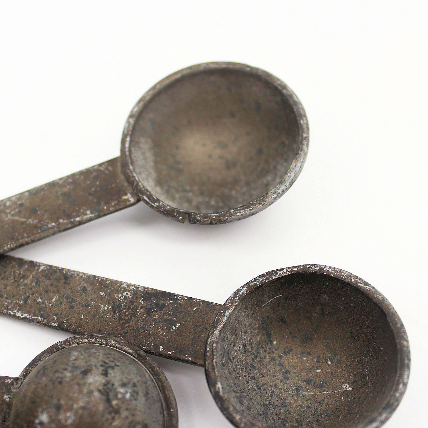 Set of rustic metal measuring spoons on a white background