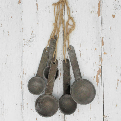 Set of vintage-style metal measuring spoons hanging on a string against a white background