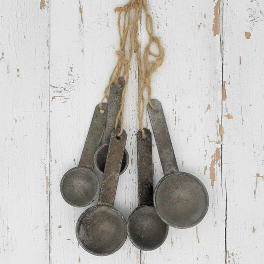 Set of vintage-style metal measuring spoons hanging on a string against a white background