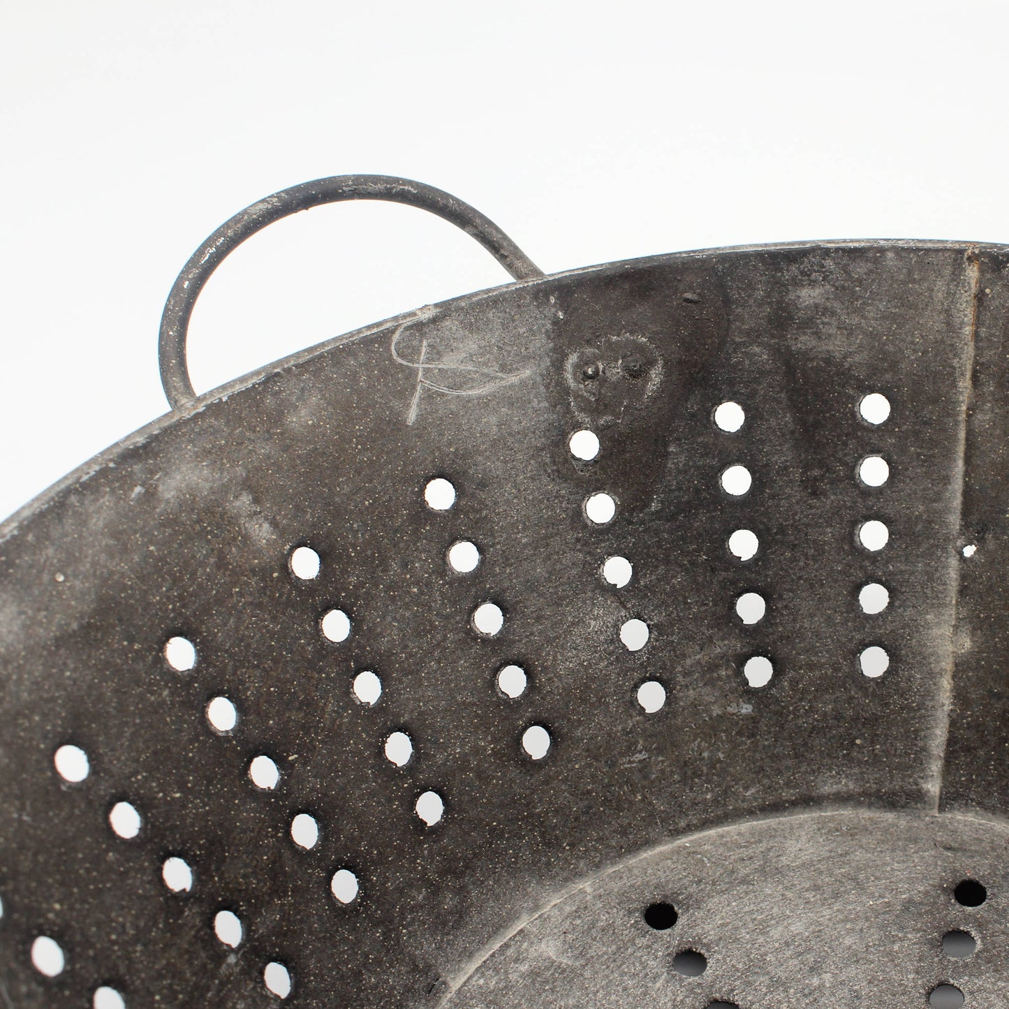 Close-up of a metal colander with holes on a white background