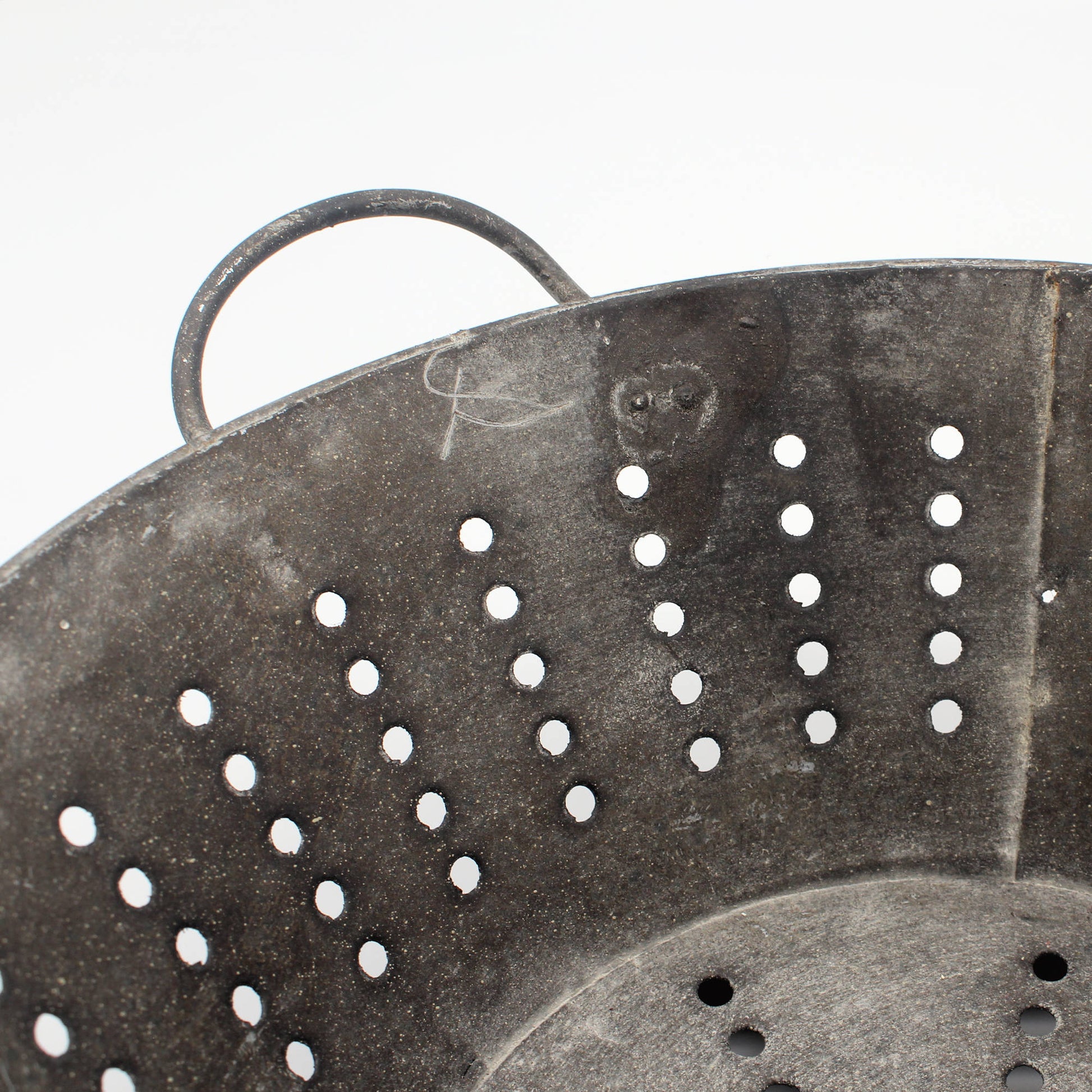 Close-up of a metal colander with holes on a white background
