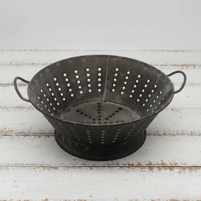 Highly distressed decorative metal colander on a white background