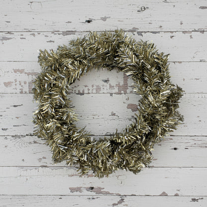 Decorative candle ring with metallic tinsel on a plain background