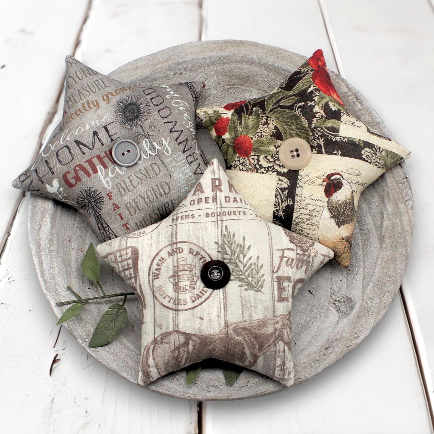 Decorative fabric stars bowl fillers with various patterns and text on a wooden plate.