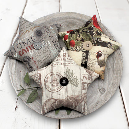 Decorative fabric stars bowl fillers with various patterns and text on a wooden plate.