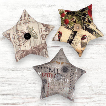 Three star-shaped decorative bowl fillers with vintage designs on a wooden surface.