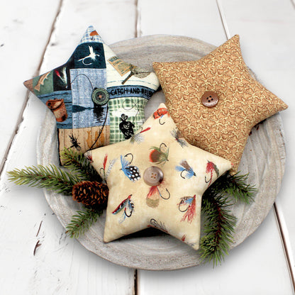 Star-shaped decorative pillows with fishing-themed designs on a wooden surface