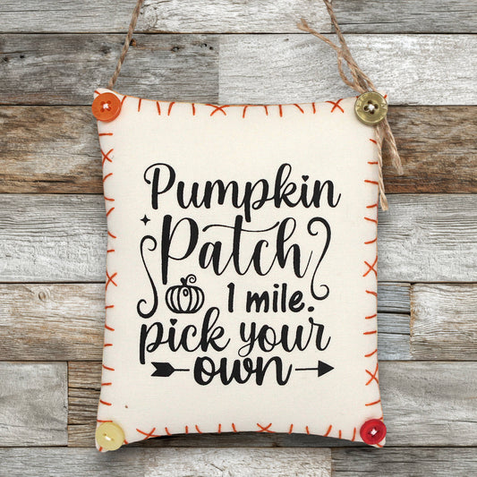 Fabric sign ornament with 'Pumpkin Patch 1 mile. Pick your own' text on a wooden background