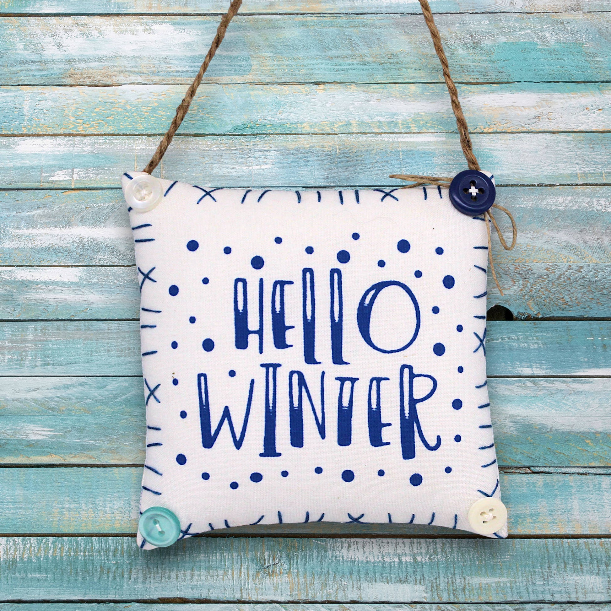 Decorative sign ornament with 'Hello Winter' text on a wooden background