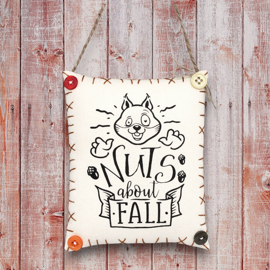 Decorative sign ornament with a squirrel design and 'Nuts about Fall' text on a wooden background
