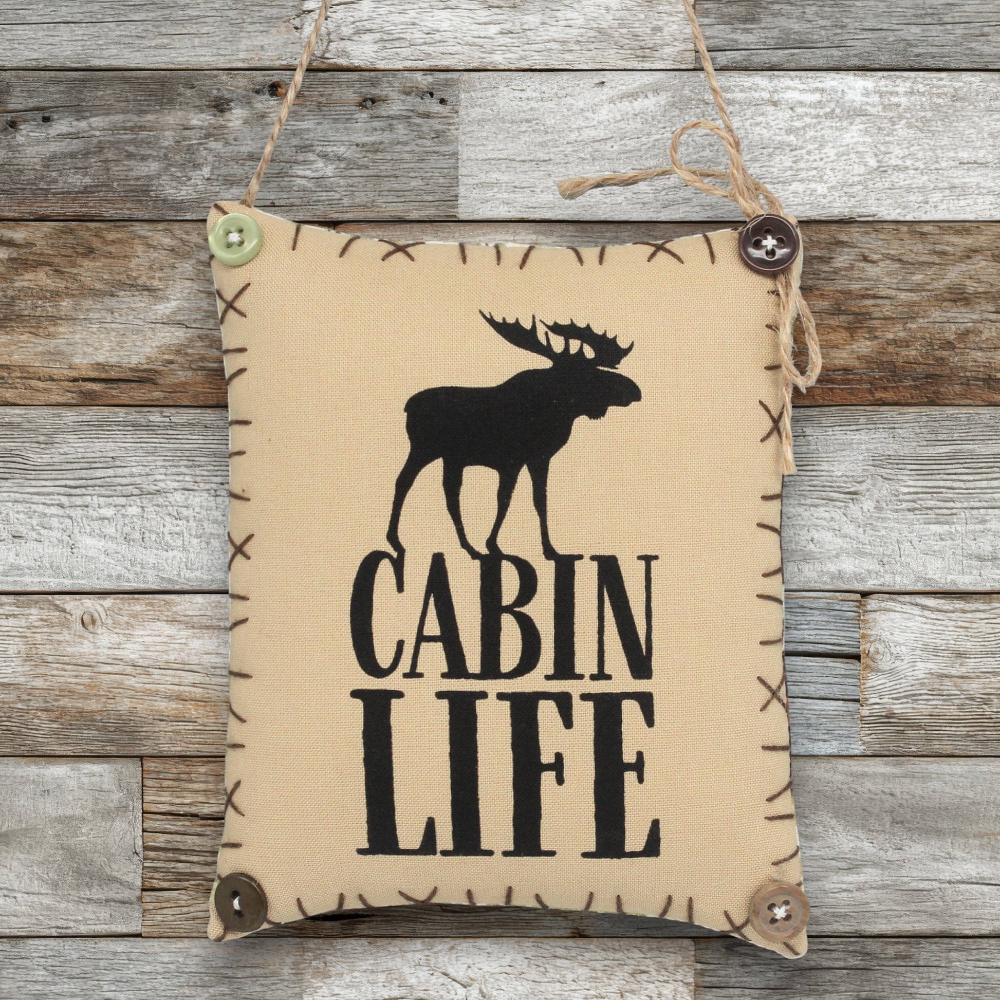 Fabric sign ornament with moose silhouette and 'Cabin Life' text on a wooden background