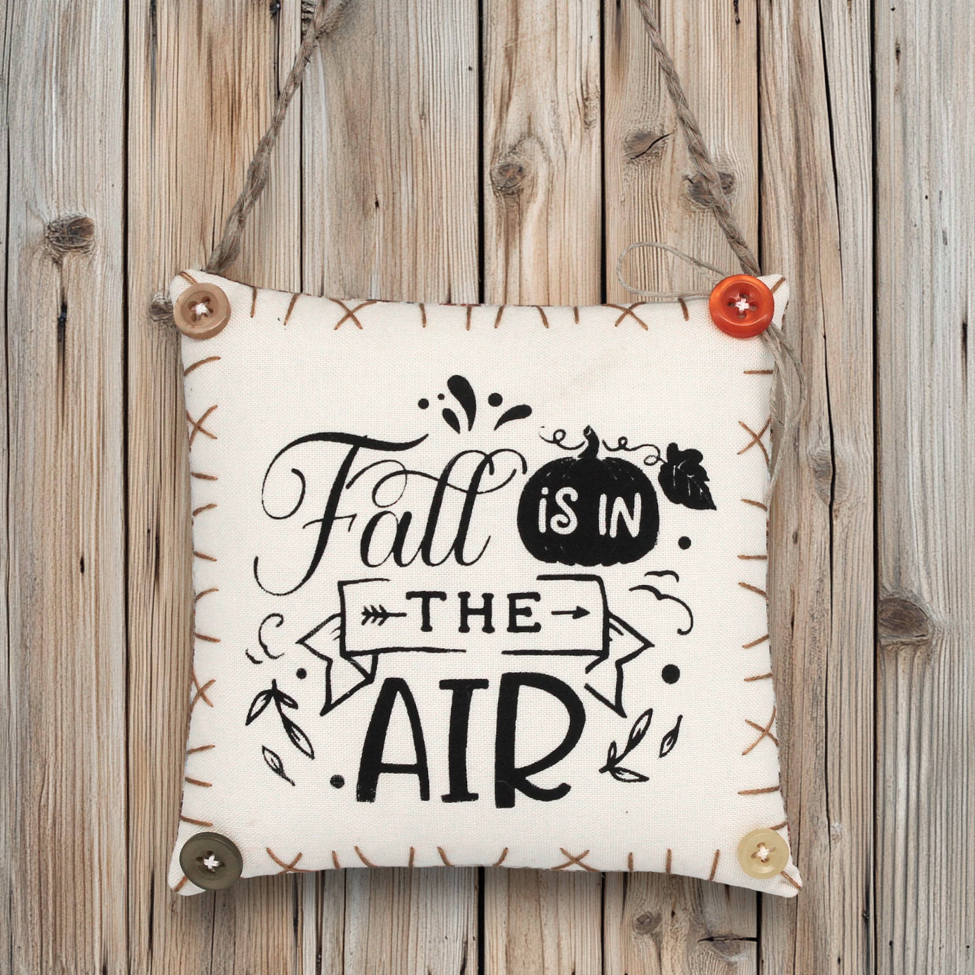 Decorative sign ornament with 'Fall is in the Air' text on a wooden background