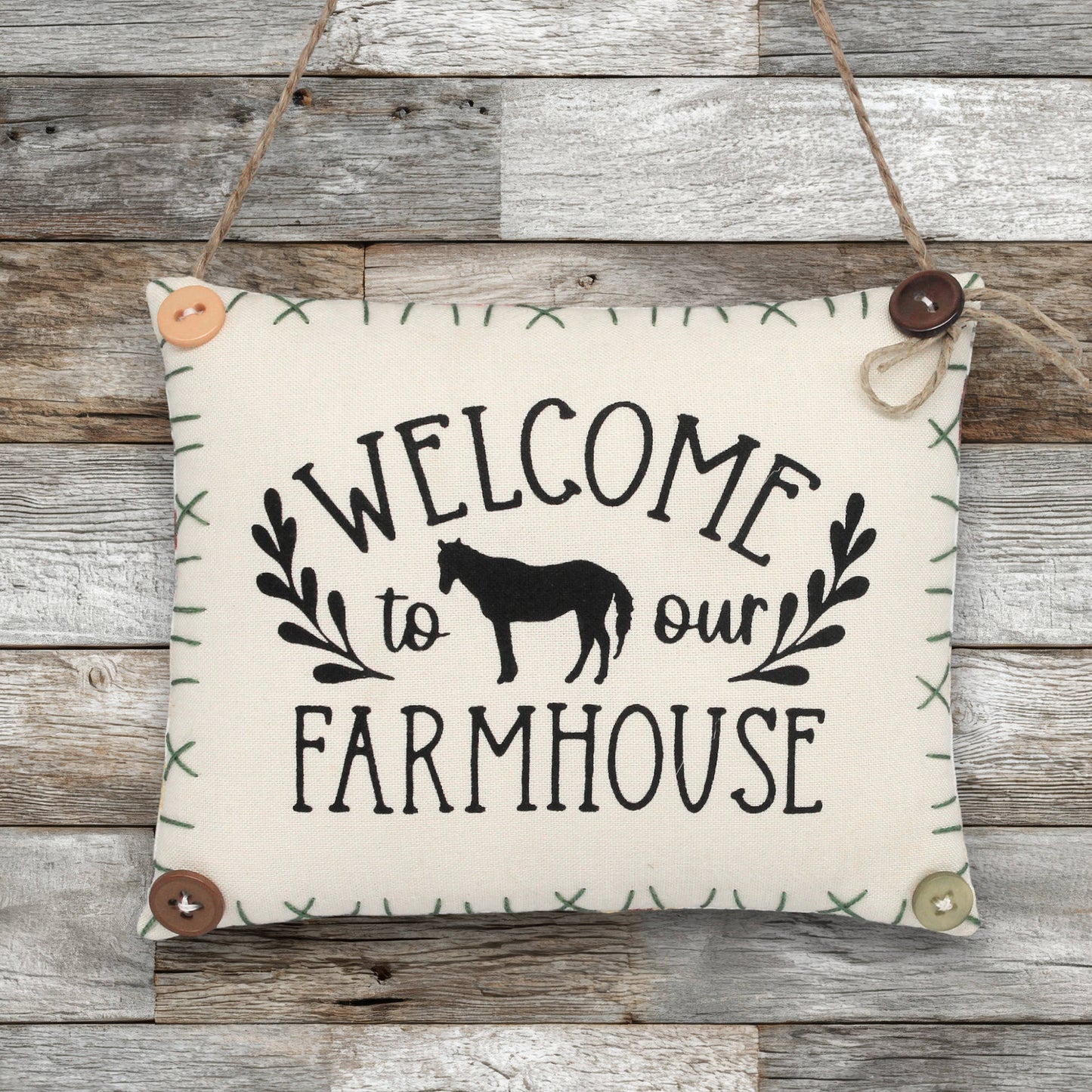 Fabric sign with 'Welcome to our Farmhouse' text and horse silhouette on a wooden background