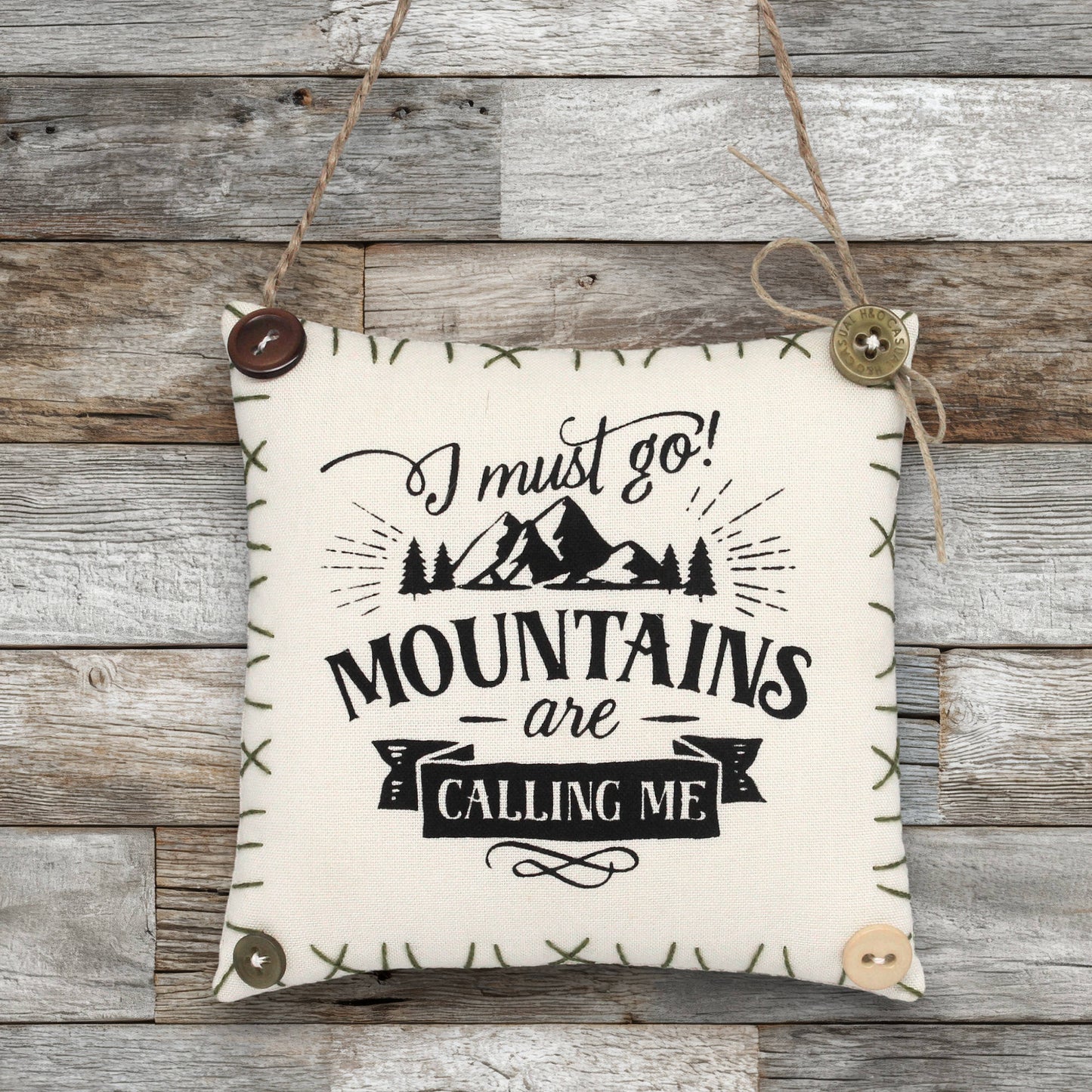Fabric sign ornament with 'Mountains are calling me' text on a wooden background