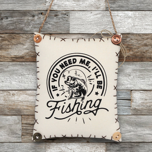 Fabric sign ornament with fishing graphic and text on a wooden background