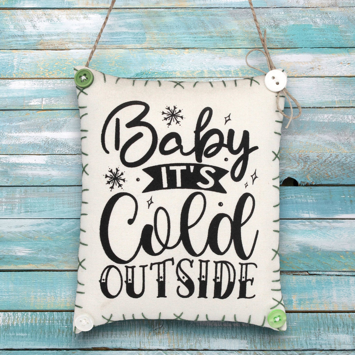 Fabric sign ornament with 'Baby It's Cold Outside' text on a wooden background