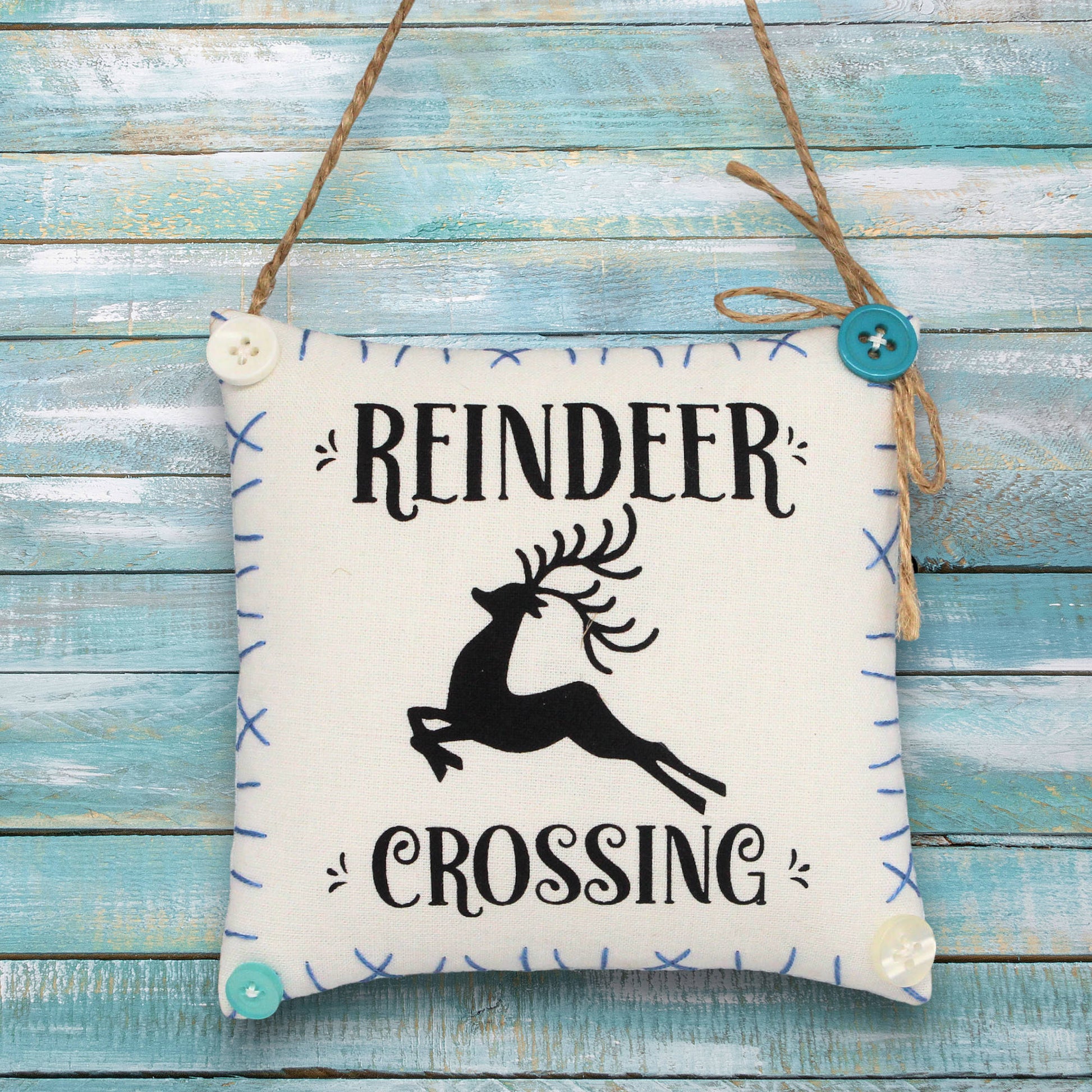 Decorative sign ornament with 'Reindeer Crossing' text and reindeer silhouette on a wooden background
