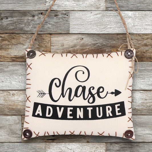 Fabric sign ornament with 'Chase Adventure' text on a wooden background