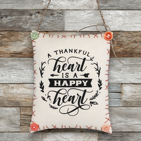 Decorative sign ornament with 'A thankful heart is a happy heart' text on a wooden background