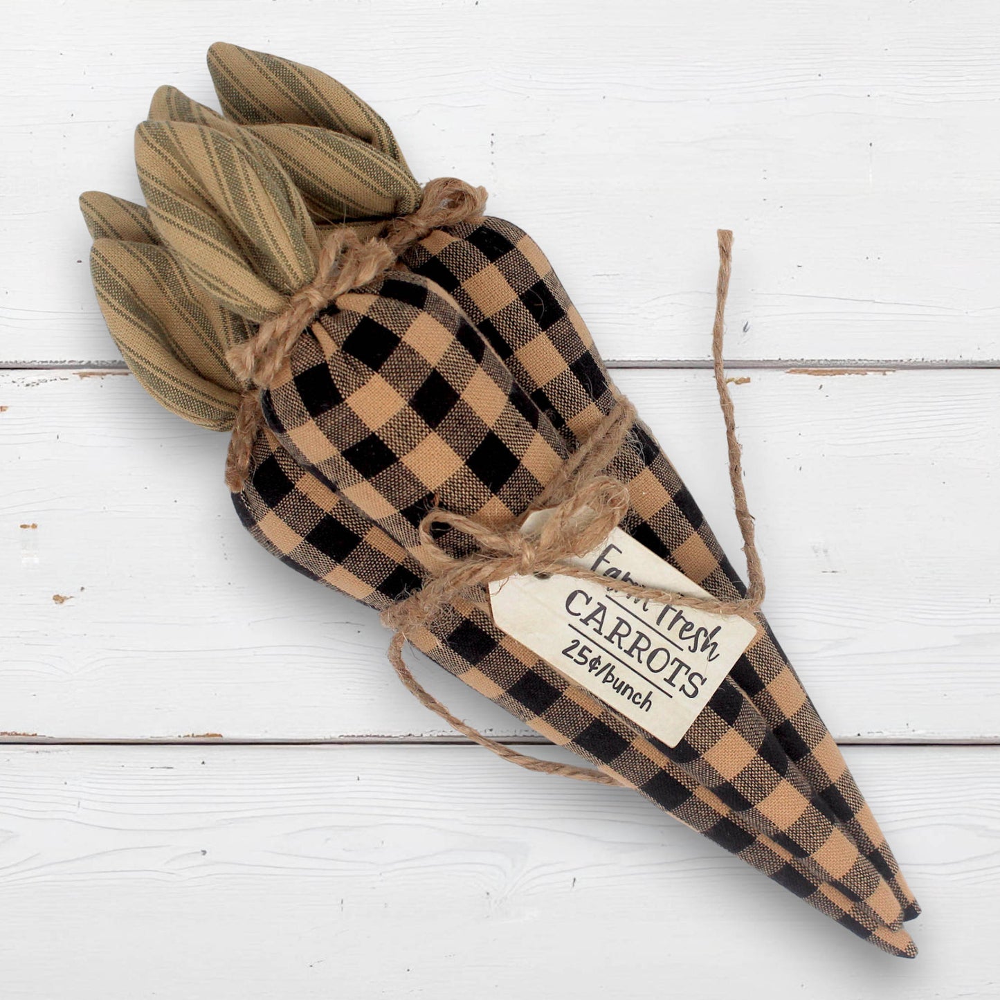 Decorative carrot made of fabric with a checkered pattern on a white wooden background