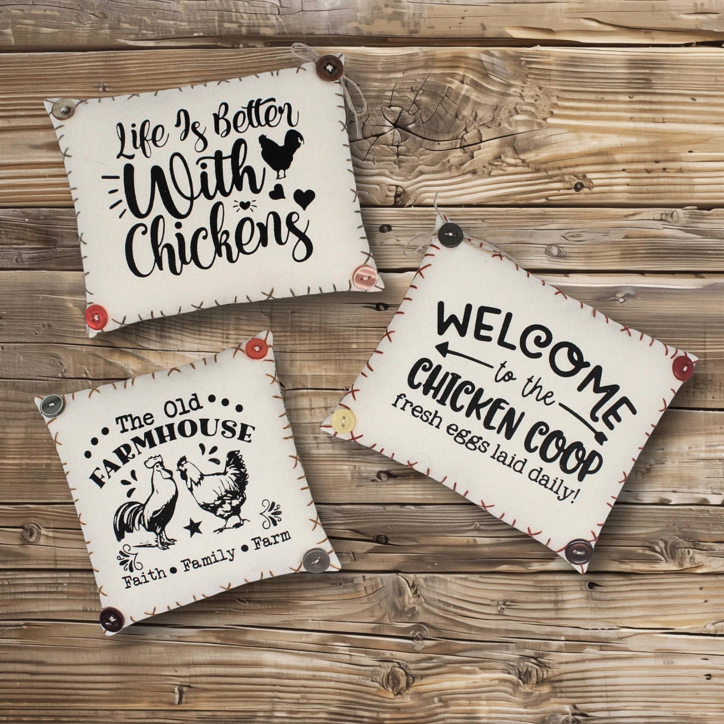 Three decorative signs with chicken-themed text on a wooden surface