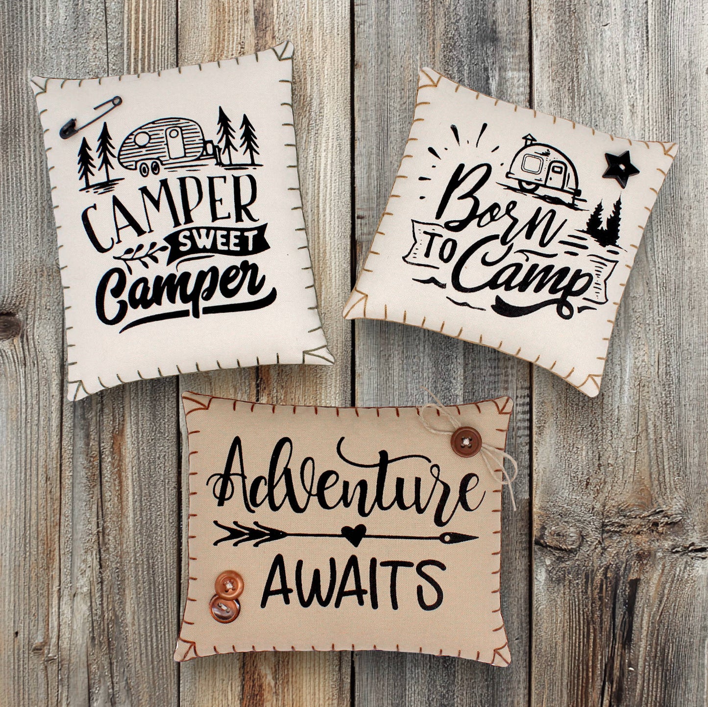 Three decorative signs with camping-themed text on a wooden background