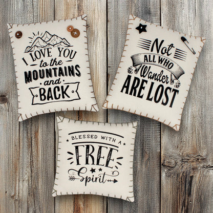 Three decorative handmade mini pillow bowl fillers screen-printed with motivational quotes about being in the mountains and having a wandering free spirit